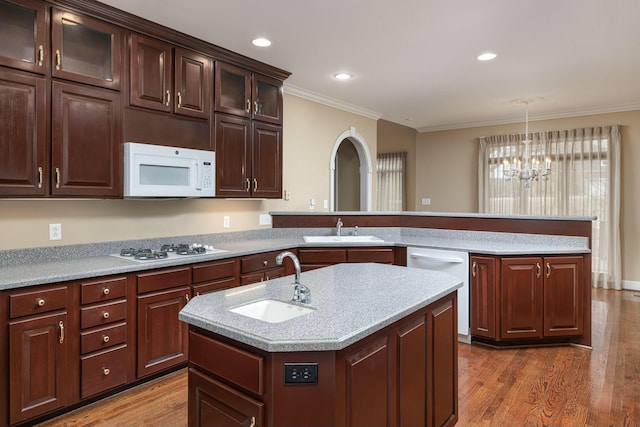 kitchen featuring sink, an island with sink, decorative light fixtures, and white appliances