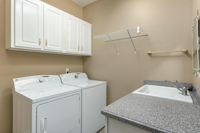 washroom with cabinets, sink, and washing machine and clothes dryer