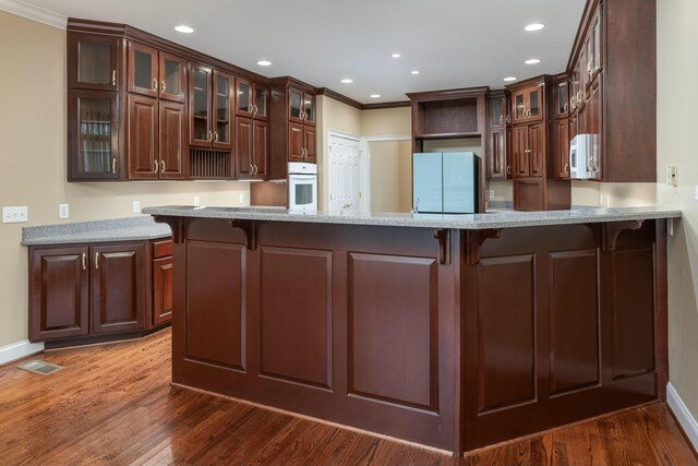 kitchen with kitchen peninsula, dark hardwood / wood-style flooring, and white appliances