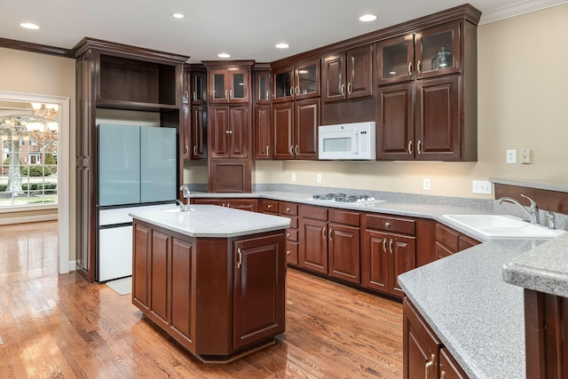 kitchen with dark brown cabinetry, sink, light hardwood / wood-style floors, and white appliances