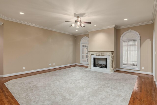 unfurnished living room with a high end fireplace, wood-type flooring, ceiling fan, and ornamental molding