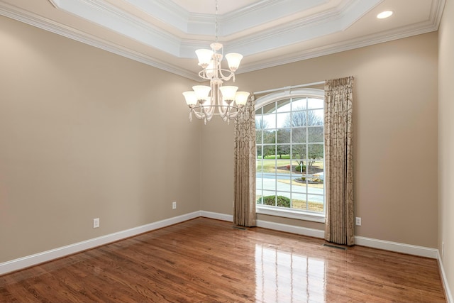 empty room with a chandelier, a tray ceiling, plenty of natural light, and ornamental molding