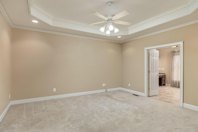 empty room featuring a tray ceiling, ceiling fan, crown molding, and light colored carpet