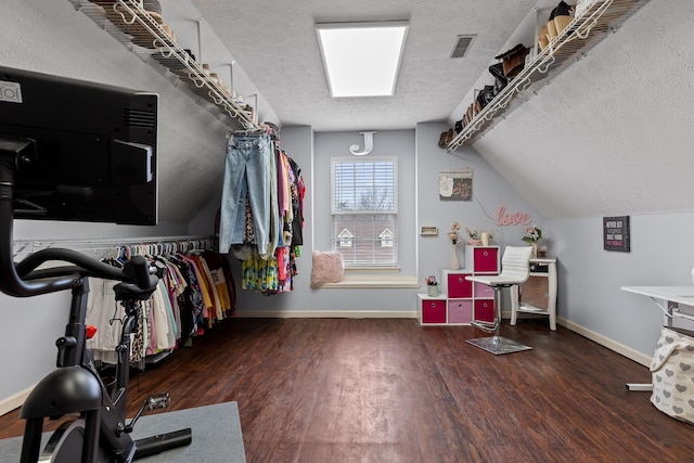 spacious closet with dark hardwood / wood-style flooring and vaulted ceiling