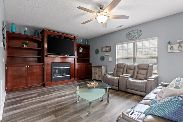 living room with ceiling fan, light hardwood / wood-style floors, and a textured ceiling