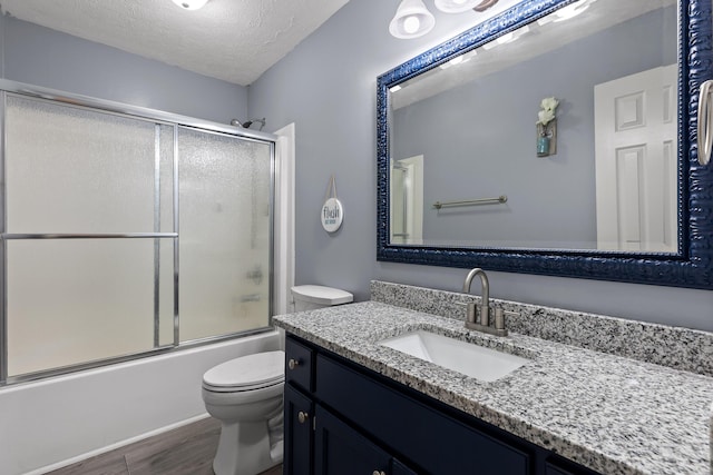 full bathroom with toilet, bath / shower combo with glass door, a textured ceiling, vanity, and hardwood / wood-style flooring