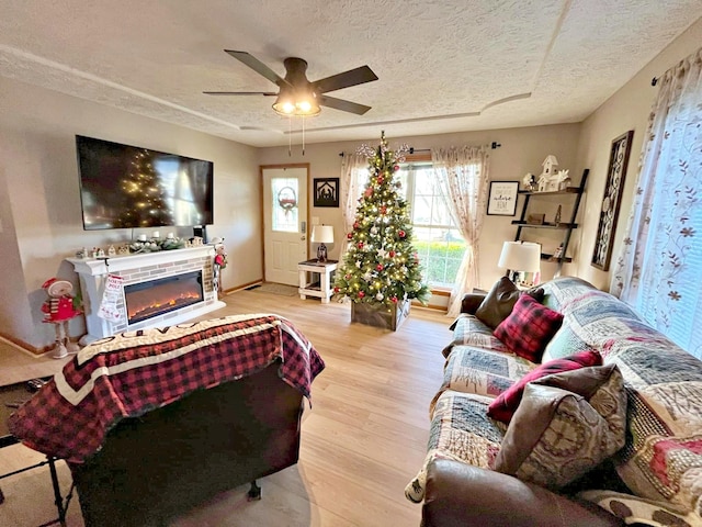 living room featuring ceiling fan, a textured ceiling, and light hardwood / wood-style flooring