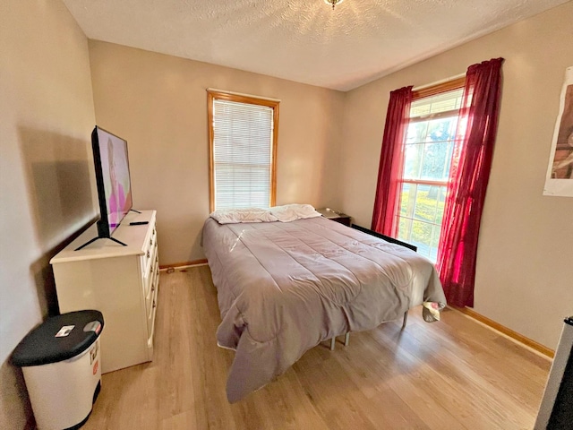 bedroom with light hardwood / wood-style floors and a textured ceiling