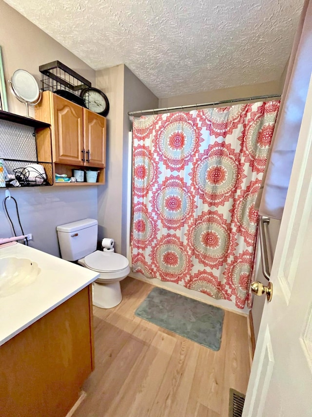 full bathroom with vanity, toilet, a textured ceiling, shower / tub combo with curtain, and wood-type flooring