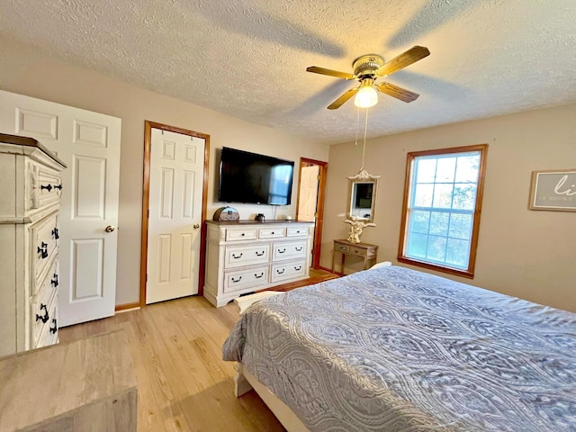 bedroom with a textured ceiling, light hardwood / wood-style flooring, and ceiling fan