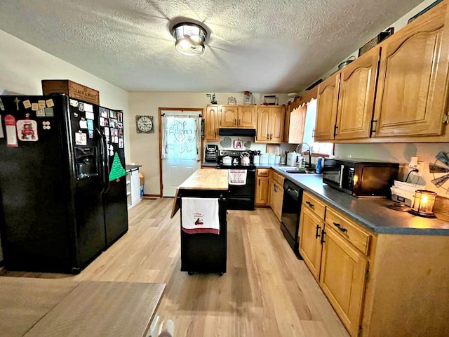 kitchen with sink, light hardwood / wood-style floors, a textured ceiling, a kitchen island, and black appliances