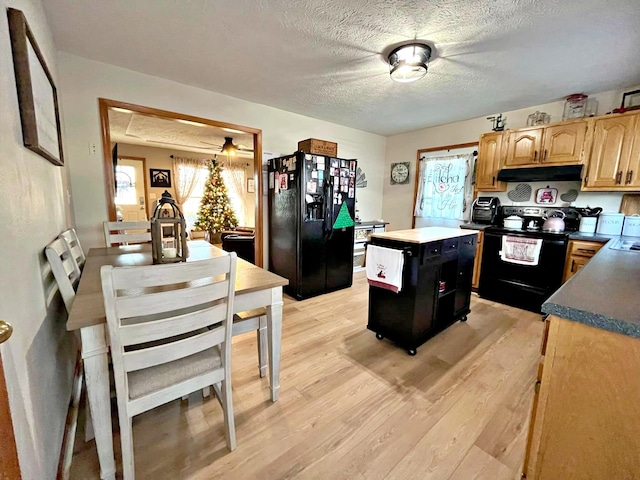 kitchen with black appliances, a center island, light hardwood / wood-style floors, and a textured ceiling