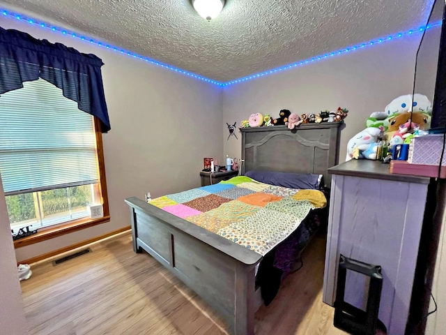 bedroom with a textured ceiling and light wood-type flooring