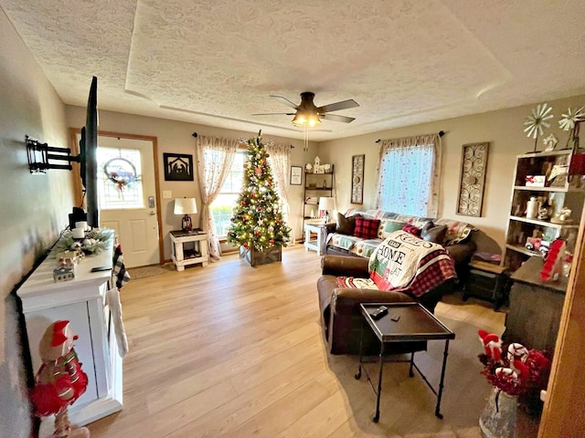 living room with a textured ceiling, light hardwood / wood-style flooring, and ceiling fan