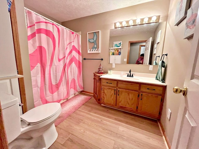 bathroom with vanity, a textured ceiling, hardwood / wood-style flooring, toilet, and curtained shower