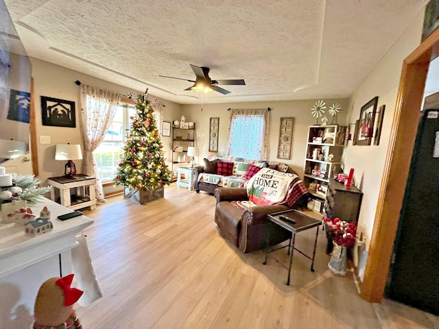 living room featuring ceiling fan, a textured ceiling, and hardwood / wood-style flooring