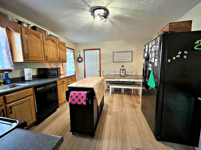 kitchen with light hardwood / wood-style flooring, black appliances, a textured ceiling, and sink