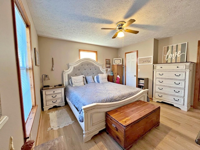 bedroom with ceiling fan, light hardwood / wood-style floors, and a textured ceiling