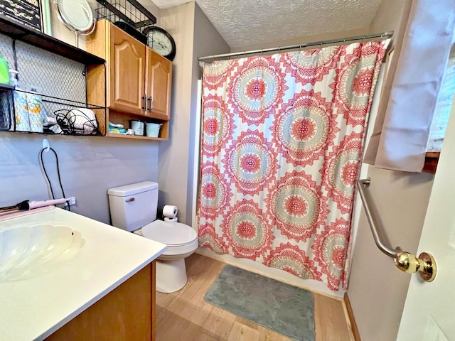 full bathroom with vanity, hardwood / wood-style flooring, toilet, a textured ceiling, and shower / tub combo