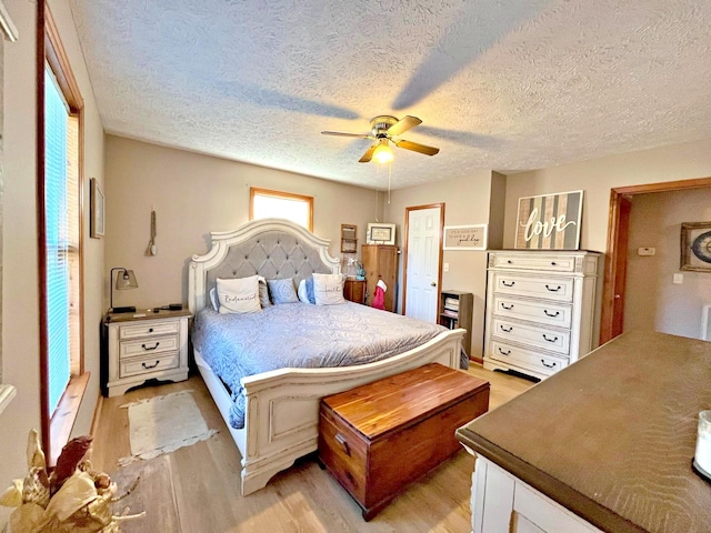 bedroom with a textured ceiling, light wood-type flooring, and ceiling fan