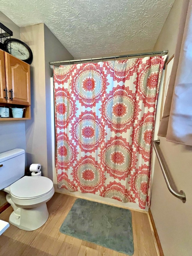 bathroom with hardwood / wood-style floors, shower / bath combo, a textured ceiling, and toilet