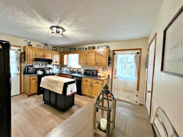 kitchen featuring a textured ceiling, sink, black appliances, light hardwood / wood-style floors, and a kitchen island