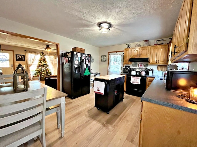 kitchen with black appliances, a center island, a textured ceiling, and light hardwood / wood-style flooring