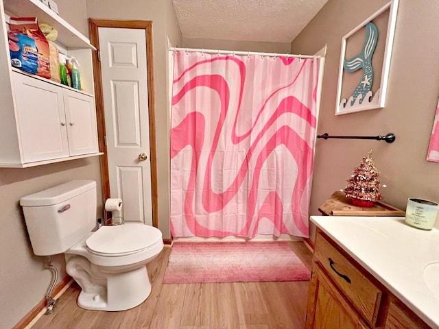 bathroom featuring vanity, wood-type flooring, a textured ceiling, and toilet