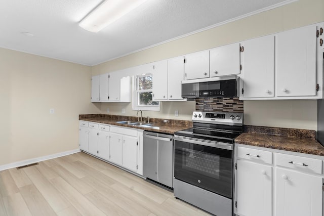 kitchen with appliances with stainless steel finishes, light wood-type flooring, a textured ceiling, white cabinets, and sink