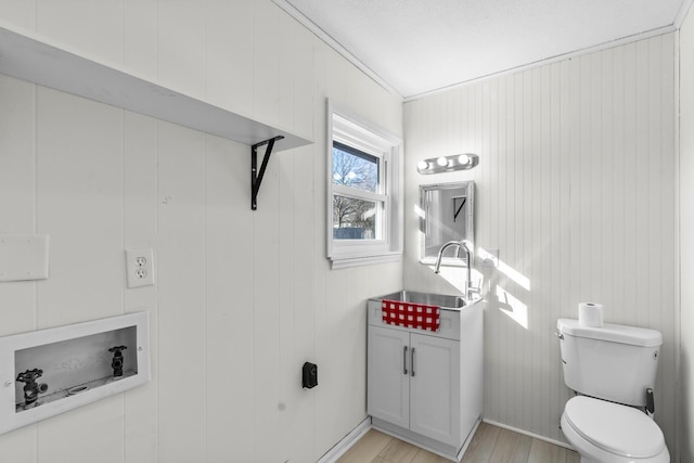 bathroom with sink, wooden walls, toilet, and hardwood / wood-style floors