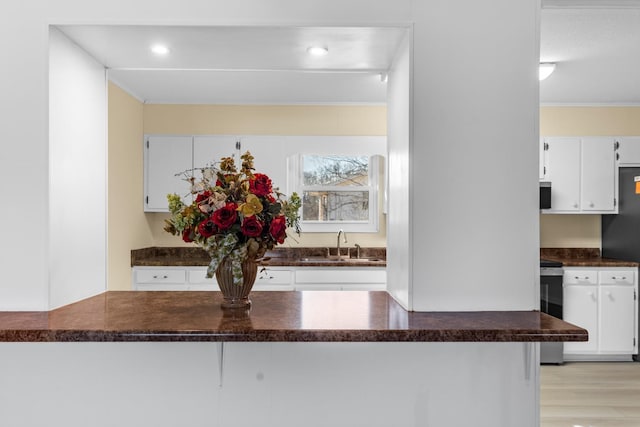 kitchen with sink, fridge, white cabinetry, and stove