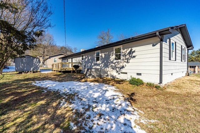 rear view of house featuring a storage shed, a lawn, and a wooden deck