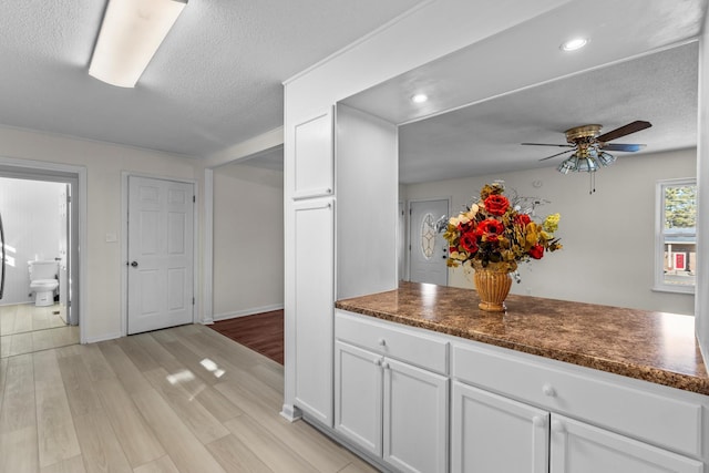 kitchen featuring white cabinetry, ceiling fan, a textured ceiling, and light hardwood / wood-style flooring