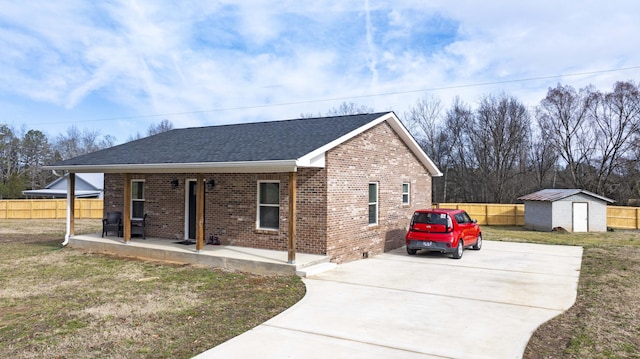 view of front of property featuring a porch, a storage shed, and a front yard