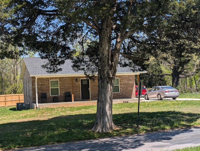 view of front of property featuring a front lawn, brick siding, fence, and a shingled roof