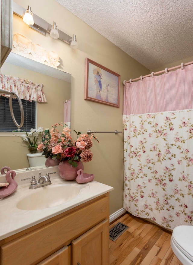 bathroom featuring vanity, wood-type flooring, a textured ceiling, and toilet