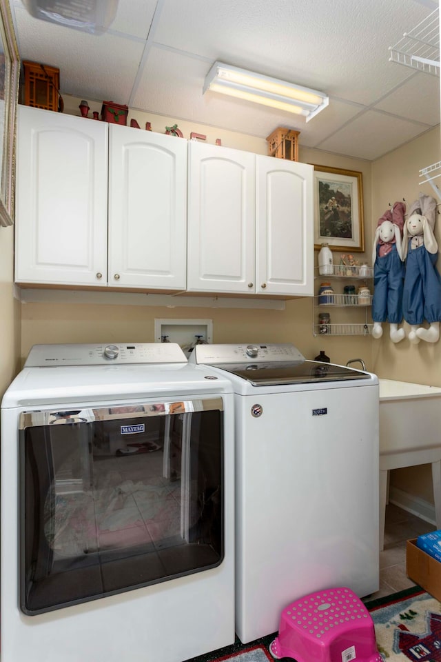 laundry area featuring tile patterned floors, separate washer and dryer, and cabinets