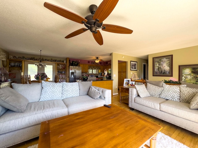 living room with ceiling fan with notable chandelier, wood-type flooring, and a textured ceiling