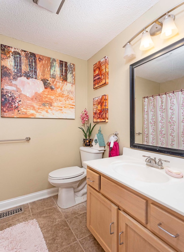 bathroom featuring tile patterned flooring, a textured ceiling, vanity, and toilet