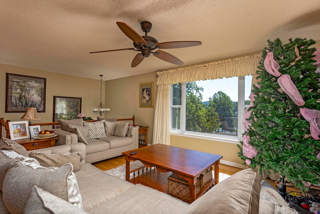 living room with hardwood / wood-style flooring, ceiling fan, and a textured ceiling