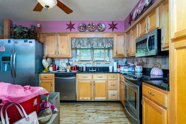 kitchen with backsplash, sink, light hardwood / wood-style flooring, a textured ceiling, and stainless steel appliances