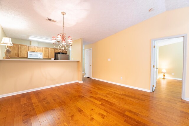 7826 Stone Garden Way, Powell, TN 37849 - unfurnished living room with a chandelier, light wood-style floors, baseboards, and a textured ceiling