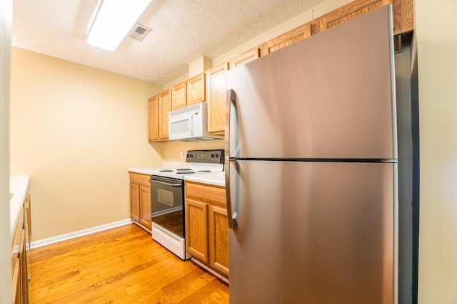 7826 Stone Garden Way, Powell, TN 37849 - kitchen featuring freestanding refrigerator, range with electric cooktop, white microwave, light wood-style flooring, and light countertops