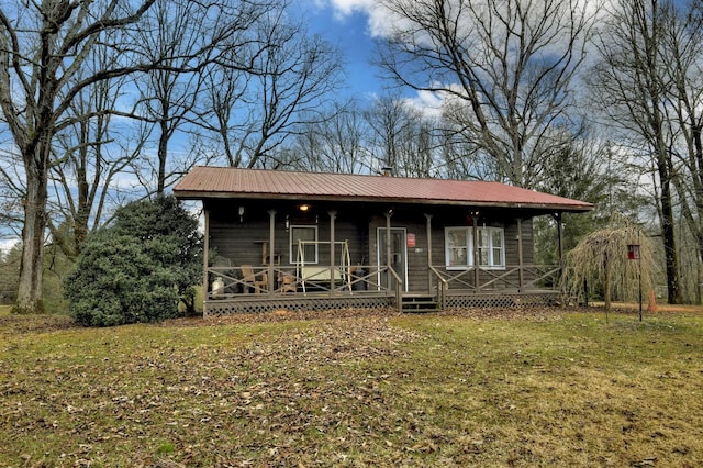 view of front facade with metal roof, a chimney, a porch, and a front yard