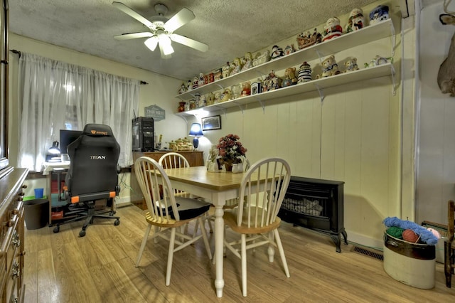 dining room with a ceiling fan, visible vents, a textured ceiling, and wood finished floors