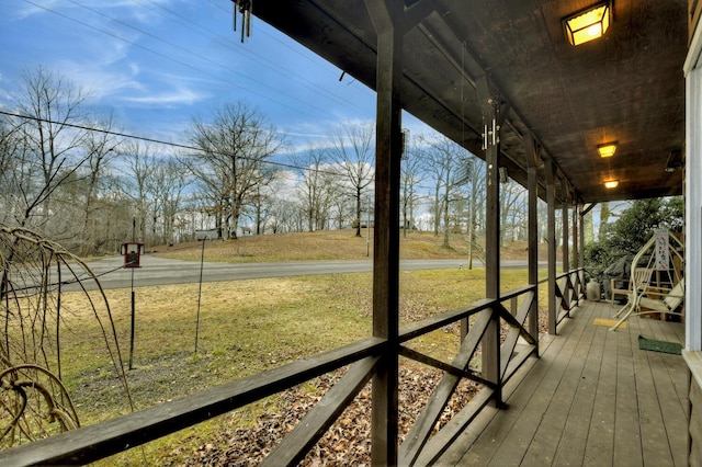 wooden terrace featuring a lawn and a porch