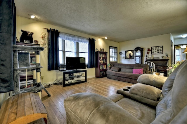 living area with baseboards, a textured ceiling, and wood-type flooring