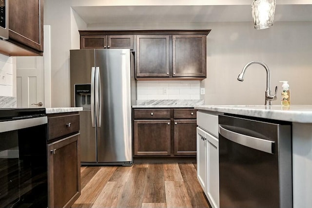 kitchen featuring stainless steel appliances, dark wood-style flooring, dark brown cabinets, and tasteful backsplash