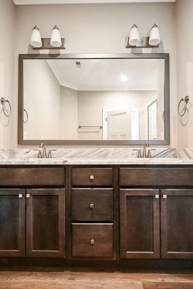 full bath featuring wood finished floors, a sink, and double vanity
