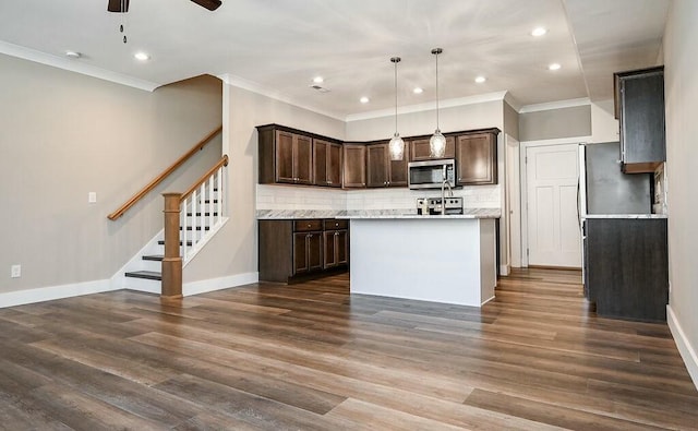 kitchen with dark brown cabinets, stainless steel microwave, backsplash, and dark wood finished floors